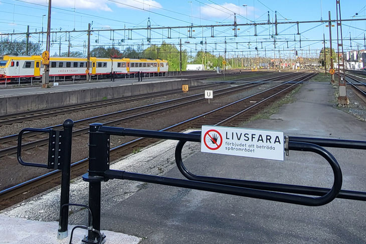 Bild på järnvägsområde med avspärrning. Skylt på avspärrning med texten "Livsfarligt".