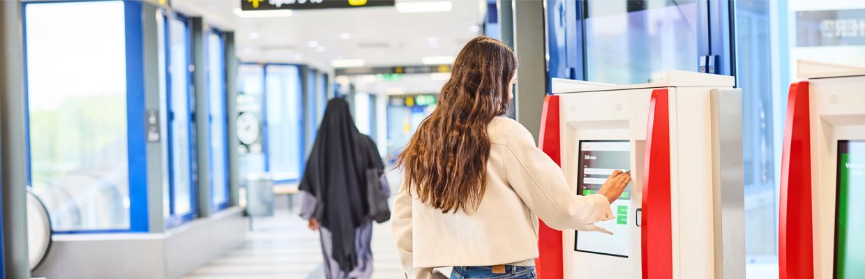 Tjej står vid biljettautomat och ska köpa biljett