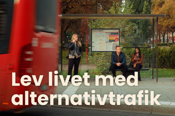 Tre personer står på busshållplats. Buss i förgrunden.