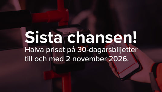 En hand håller i en mobiltelefon och på skärmen syns en biljett i appen. Biljetten hålls upp mot en validator ombord på en buss.